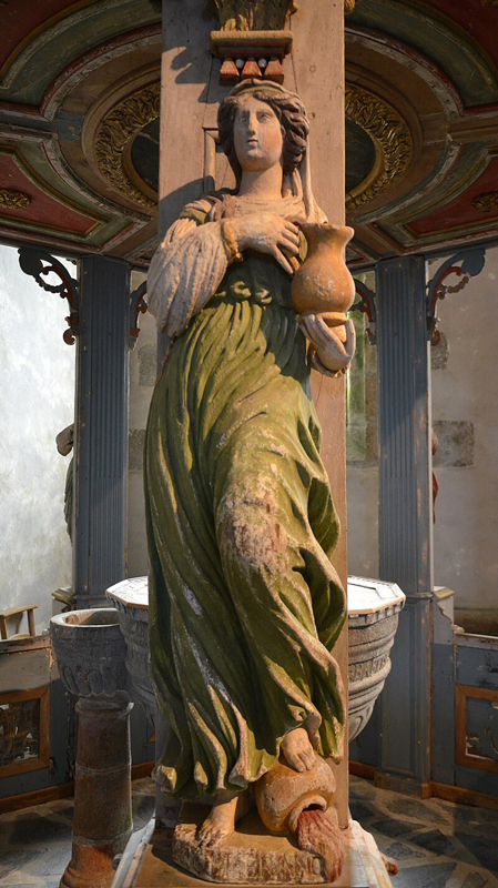 Représentation de la tempérance, sculpture de bois peint, datée de 1683, sur l'édicule qui couvre la cuve baptismale de l'église bretonne de Commana. La figure renverse du pied une cruche de vin, et tient une cruche d'eau.